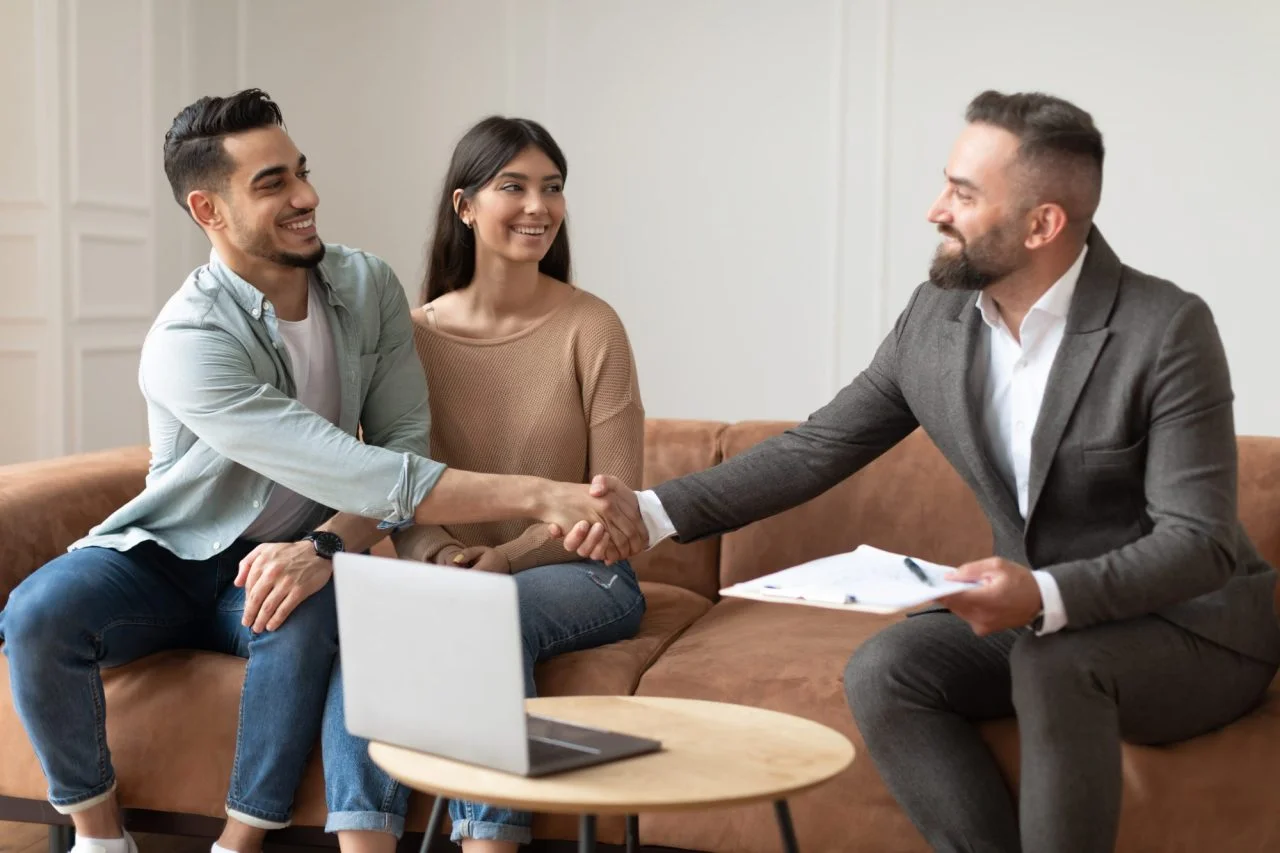millennial-couple-buying-new-apartment-shaking-hands-with-realtor-e1695129370216